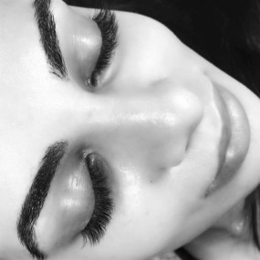 Closed eyes showing a full set of lash extensions and shaped brows